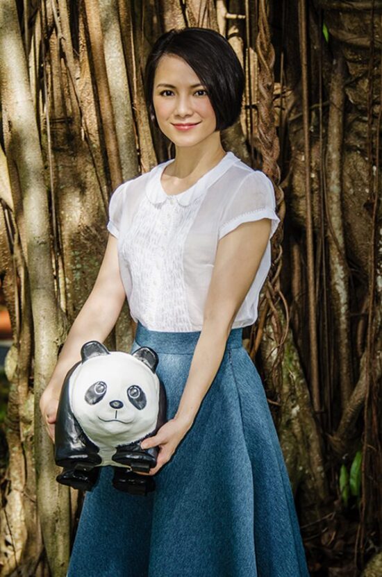 Female model in white dress outdoor fashion photoshoot with panda bear prop