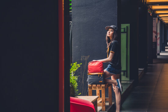 Fashion model standing with backpack against wall