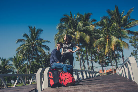 Street fashion models sitting with red suitcase