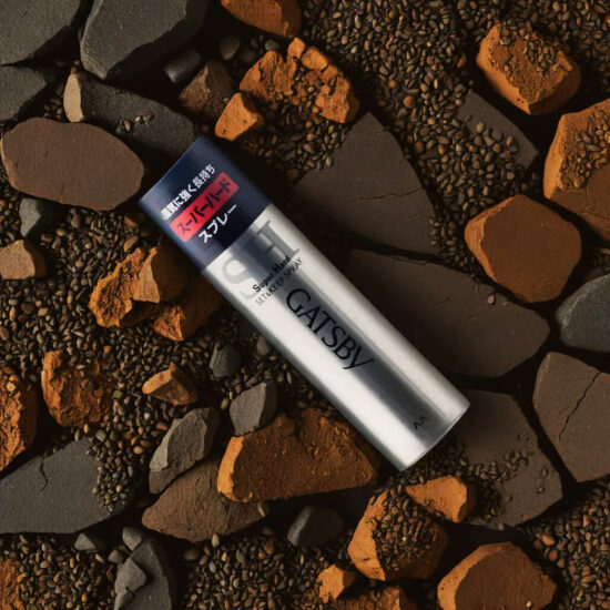 Gatsby Hair Spray bottle on brown stones – luxury beauty product photography.