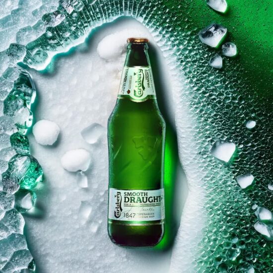Green beer bottle with ice – beverage photography.