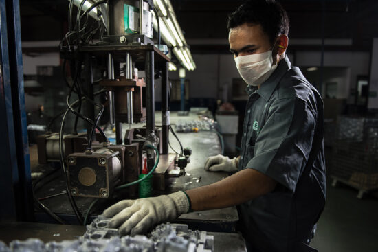 Worker at production line handling machinery in factory