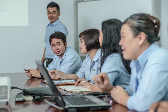 Office meeting with employees working on laptop and documents