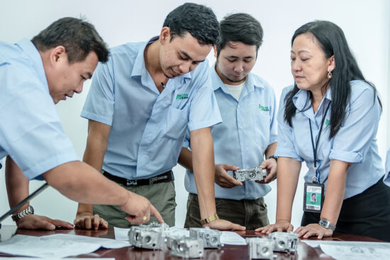 Team of engineers discussing mechanical parts in factory