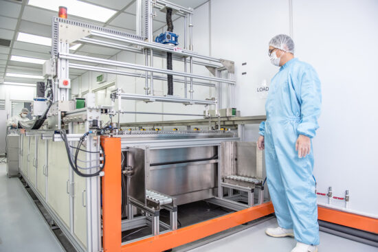 Worker in blue suit operating industrial production machine