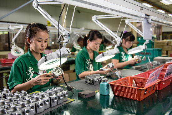 Factory workers assembling small mechanical parts