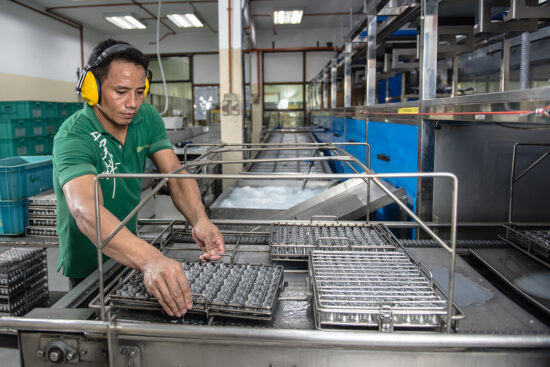 Worker handling metal parts in production line