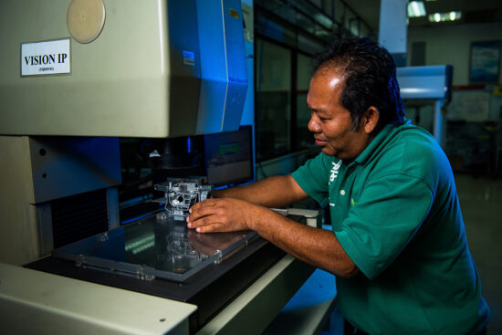 Factory worker using machine for product quality check